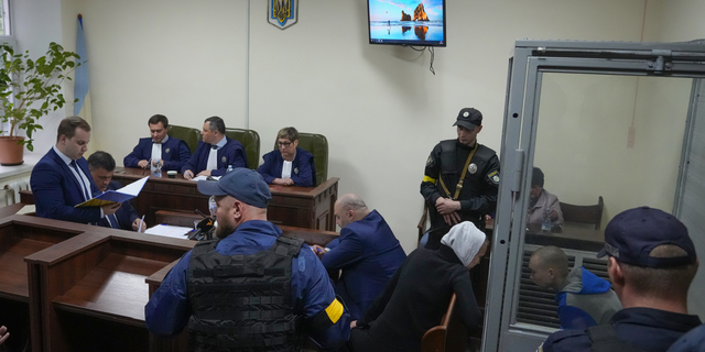 <br/>Sitting behind a glass, Russian army Sgt. Vadim Shishimarin, 21, talks with his translator, center right, during a court hearing in Kyiv, Ukraine, on Wednesday, May 18.