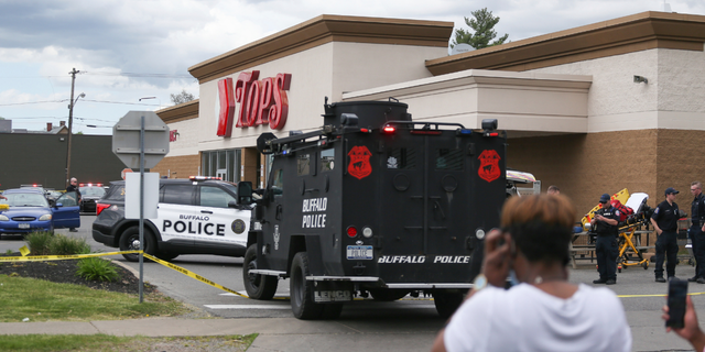 A crowd gathers as police investigate after a shooting at a supermarket on Saturday, May 14, 2022, in Buffalo, N.Y. Multiple people were shot at the Tops Friendly Market. Police have notified the public that the alleged shooter was in custody.