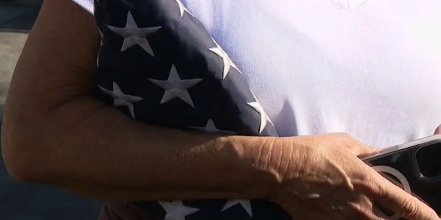 An Orange County mother clutches the U.S. flag that firefighters were able to salvage during the Coastal Fire.