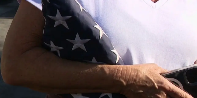 An Orange County mother clutches the U.S. flag that firefighters were able to salvage during the Coastal Fire.