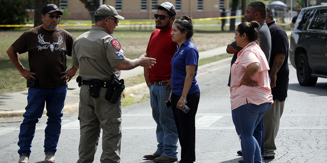 A policeman talks to people asking for information outside of the Robb Elementary School in Uvalde, Texas, on Tuesday, May 24.