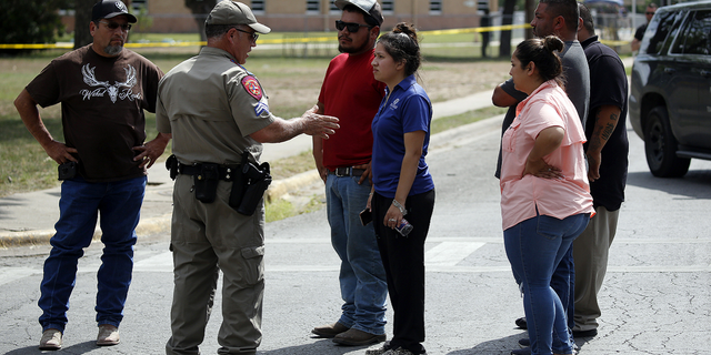 A policeman talks to people asking for information outside of the Robb Elementary School in Uvalde, Texas, on Tuesday, May 24.