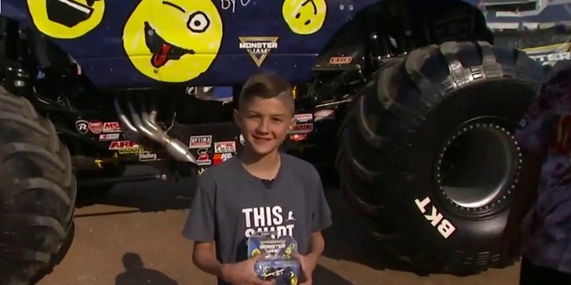 St. Jude patient Calvin holds up his Monster Jam toy truck while posing with the featured Monster Jam monster truck decorated with his original design on "Fox and Friends," on May 19, 2022. (Fox News)