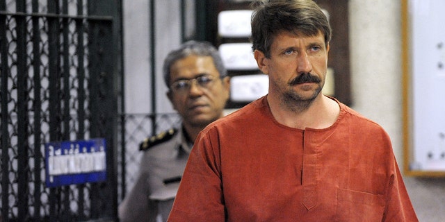 Alleged Russian arms dealer Viktor Bout (R) walks past temporary cells ahead of a hearing at the Bangkok criminal court on August 20, 2010.