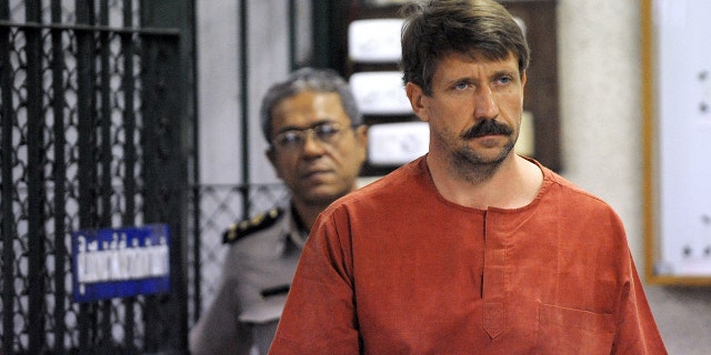 Russian alleged arms dealer Viktor Bout (right) walks past a temporary cell ahead of a hearing at the Criminal Court in Bangkok on August 20, 2010.