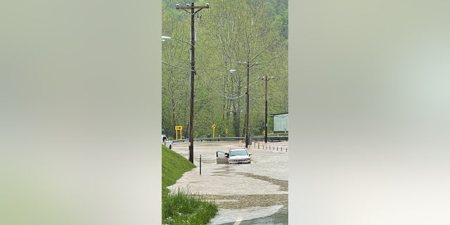 A person exits his vehicle as it submerges in flood water in Spencer, West Virginia
