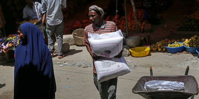 A man carries a sack of wheat flour imported from Turkey in the Hamar-Weyne market in the capital Mogadishu, Somalia Thursday, May 26, 2022. Families across Africa are paying about 45% more for wheat flour as Russia's war in Ukraine blocks exports from the Black Sea. Some countries like Somalia get more than 90% of their wheat from Russia and Ukraine. That's forcing many people to substitute wheat for other grains. But the United Nations is warning that the price hikes are coming as many parts of Africa are facing drought and hunger.