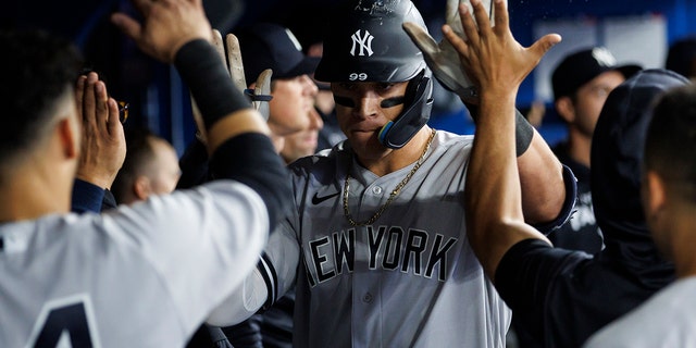 Aaron Judge #99 of the New York Yankees celebrates a solo home run in the dugout during the sixth inning of their MLB game against the Toronto Blue Jays at Rogers Centre on May 3, 2022 in Toronto, Canada. 