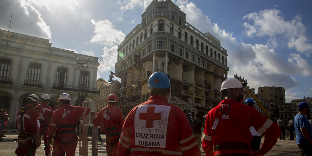 Red Cross members gather near the ruins at the site of the deadly explosion that destroyed the five-star Hotel Saratoga in Old Havana, Cuba on Sunday, May 8.