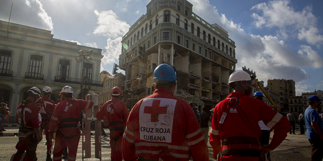 Red Cross members gather near the ruins at the site of the deadly explosion that destroyed the five-star Hotel Saratoga in Old Havana, Cuba on Sunday, May 8.