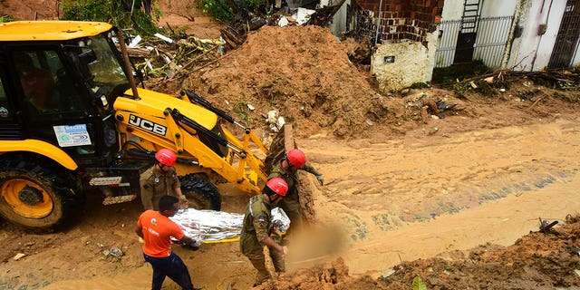 Firefighters carry a body recovered from a landslide triggered by heavy rain in the Jardim Monte Verde neighborhood of Recife in Pernambuco state, Brazil, Sunday, May 29, 2022. Landslides killed at least 84 people in the state of Pernambuco, according to authorities, and more than 1,000 people have been forced from their homes. (AP Photo/Joao Carlos Mazella)