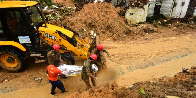 Firefighters carry a body recovered from a landslide triggered by heavy rain in the Jardim Monte Verde neighborhood of Recife in Pernambuco state, Brazil, Sunday, May 29, 2022. Landslides killed at least 84 people in the state of Pernambuco, according to authorities, and more than 1,000 people have been forced from their homes. (G3 Box News Photo/Joao Carlos Mazella)