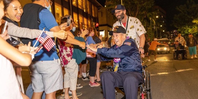 Novelist Jack Carr (standing, center) is shown accompanying an American veteran to a World War II commemorative event. Carr regularly gives back to vets who did so much for our country through their service.