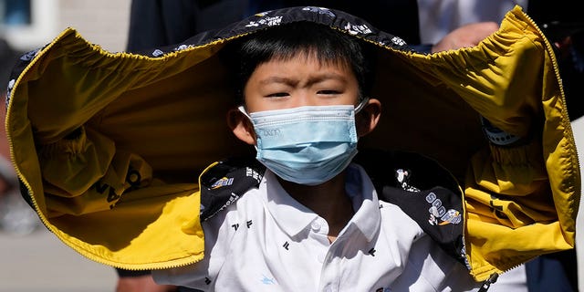 A child wearing a mask lines up for a COVID test Sunday, May 1, 2022, in Beijing. Many Chinese are marking a quiet May Day holiday this year as the government's "zero-COVID" approach restricts travel and enforces lockdowns in multiple cities.