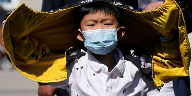 A child wearing a mask lines up for a COVID test Sunday, May 1, 2022, in Beijing. Many Chinese are marking a quiet May Day holiday this year as the government's "zero-COVID" approach restricts travel and enforces lockdowns in multiple cities.