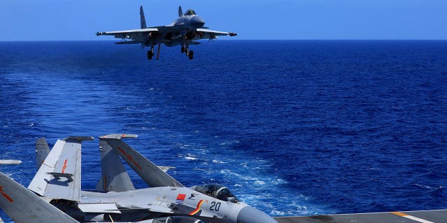 In this photo released Dec. 31, 2021, by Xinhua News Agency, an undated photo shows a carrier-based J-15 fighter jet preparing to land on the Chinese navy's Liaoning aircraft-carrier during open-sea combat training. China is holding military exercises in the disputed South China Sea coinciding with U.S. President Joe Biden's visits to South Korea and Japan that are largely focused on countering the perceived threat from China. (Hu Shanmin/Xinhua via AP)