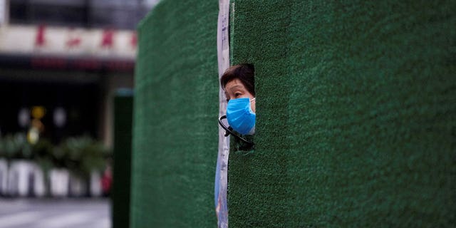 أحد السكان ينظر من خلال ثقب في الحاجز في منطقة سكنية أثناء الإغلاق وسط جائحة COVID-19 في شنغهاي ، الصين ، 6 مايو 2022. 