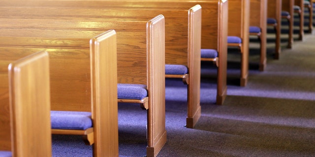 FILE- Window light is shining on rows of empty church pews in an empty church sanctuary.