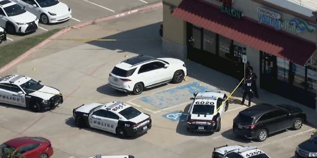 Dallas police cars surround the Hair World Salon after a gunman shot three women inside.