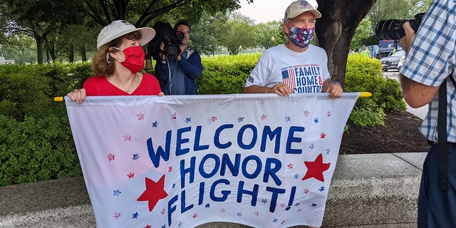 Friends, family and supporters hold an Honor Flight banner to welcome veterans. 