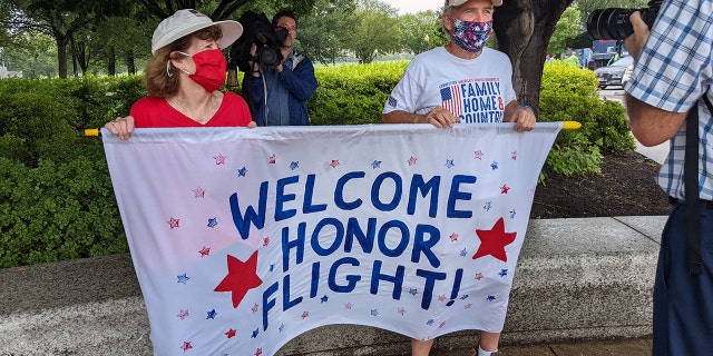 Friends, family and supporters hold an Honor Flight banner to welcome veterans.