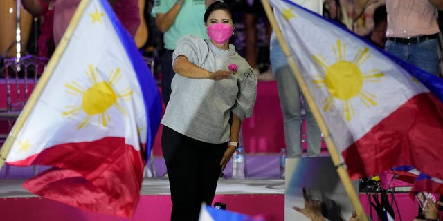 Vice President Leni Robredo greets supporters as a Philippine flag is waved during a campaign rally that coincides with her birthday in Pasay City, Philippines, on April 24, 2022.