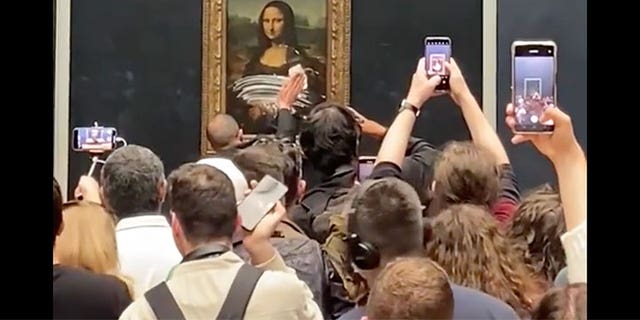 A museum staffer cleans the glass protecting the Mona Lisa at the Louvre following a climate protest stunt on Sunday. (credit: @Luke_sundberg_)