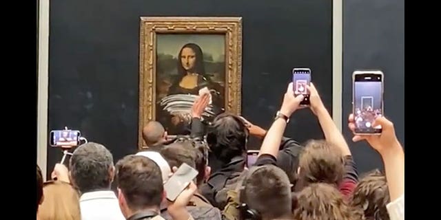 A museum staffer cleans the glass protecting the Mona Lisa at the Louvre following a climate protest stunt on Sunday. (credit: @Luke_sundberg_)