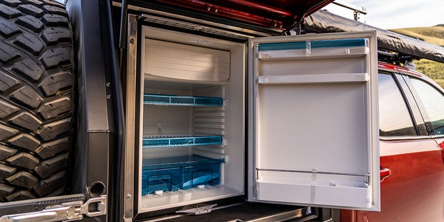 A refrigerator is powered by batteries charged by a solar panel mounted on the roof.