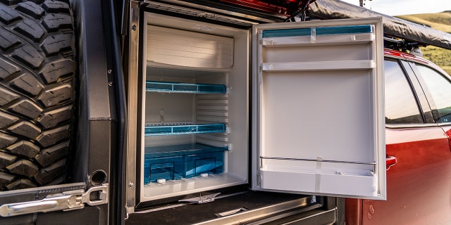 A refrigerator is powered by batteries charged by a solar panel mounted on the roof.