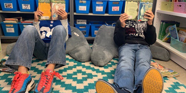 Elementary school kids sit on the floor of a classroom library while enjoying books donated by O3 Books. (Pathik Oza/O3 Books)