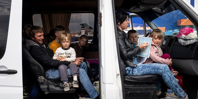 People with children wait after arrival from the Ukrainian city of Tokmak at a center for displaced people in Zaporizhzhia, Ukraine, Monday, May 2, 2022. 