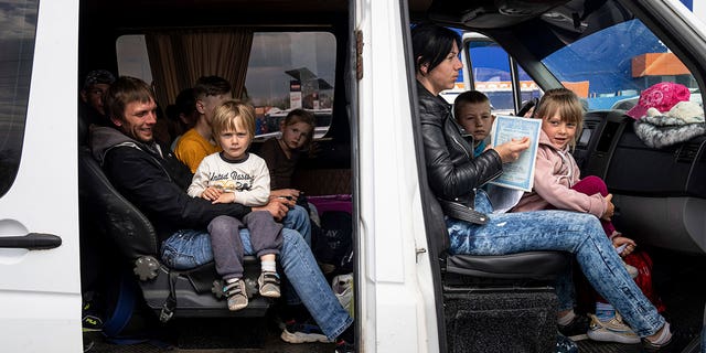 People with children wait after arrival from the Ukrainian city of Tokmak at a center for displaced people in Zaporizhzhia, Ukraine, on May 2, 2022. 