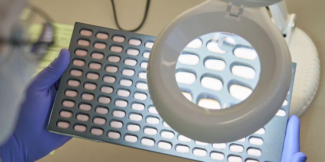 FILE - In this photo provided by Pfizer, a lab technician visually inspects COVID-19 Paxlovid tablet samples in Freiburg, Germany in December 2021. As more doctors prescribe Pfizer's powerful COVID-19 pill, new questions are emerging about its performance, including why a small number of patients appear to relapse after taking the drug.