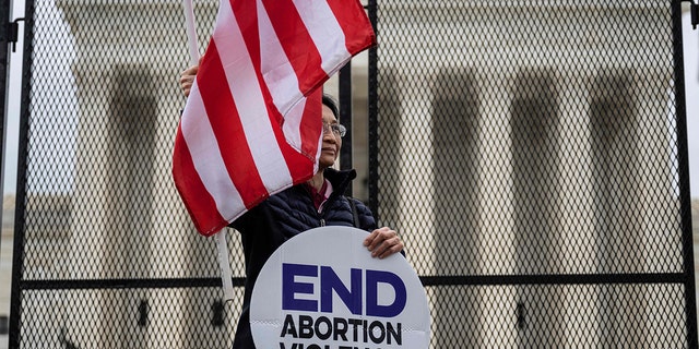 A pro-life demonstrator stands in front of an un-scalable fence that stands around the US Supreme Court in Washington, DC, on May 5, 2022. 