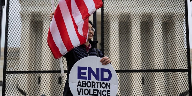 A pro-life demonstrator stands in front of an un-scalable fence that stands around the US Supreme Court in Washington, DC, on May 5, 2022. 