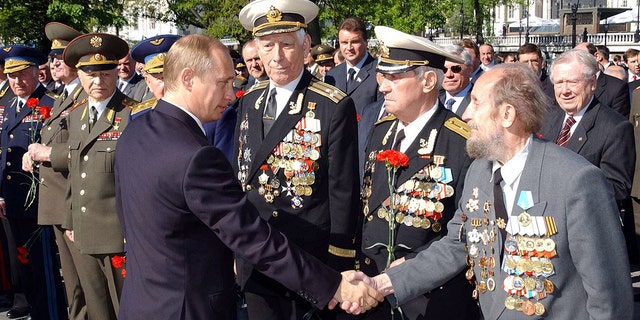 2002 年 5 月 8 日，俄罗斯总统弗拉基米尔·普京（中）在莫斯科无名烈士墓举行的献花仪式后与二战老兵握手。俄罗斯将于 5 月 9 日庆祝胜利日。