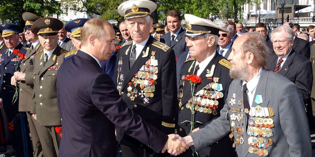 Russian President Vladimir Putin (C) shakes hands with WWII veterans after a wreath laying ceremony at the Unknown Soldier Tomb in Moscow, May 8, 2002. Russia will celebrate the Victory Day on May 9.