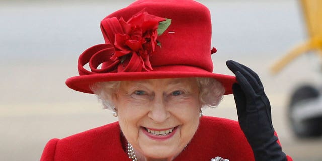 FILE - Britain's Queen Elizabeth II holds on to her hat in high winds as she arrives for a visit to RAF Valley, Anglesey, Wales on April 1, 2011.