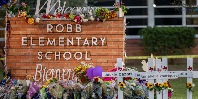 A memorial is seen surrounding the Robb Elementary School sign, following the May 24 mass shooting at the school, on May 26, 2022, in Uvalde, Texas.