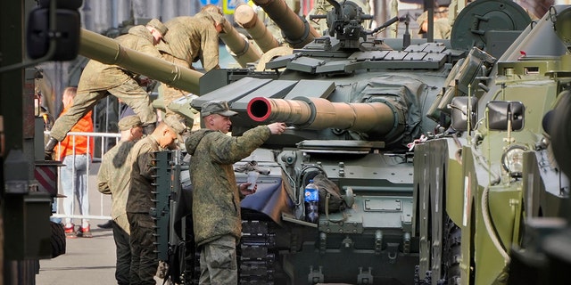 Russian soldiers color their T-72 tanks on the eve of the Victory Day military parade 