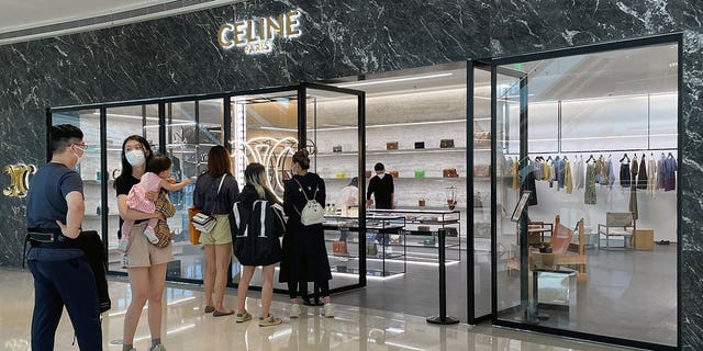 Des acheteurs portant des masques faciaux font la queue devant un magasin de la marque de luxe française Céline dans un centre commercial rouvert au milieu de l'épidémie de COVID-19 à Shanghai, en Chine, le 29 mai 2022. 