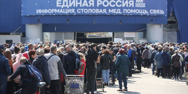 Civilians line up for humanitarian aid distributed in the United Humanitarian Center in Mariupol, in territory under the government of the Donetsk People's Republic, eastern Ukraine, Monday, May 2, 2022.