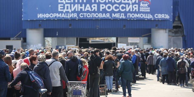 Civilians line up to receive humanitarian aid distributed at the Mariupol United Humanitarian Center in the territory under the government of the Donetsk People's Republic in eastern Ukraine on Monday, May 2, 2022.