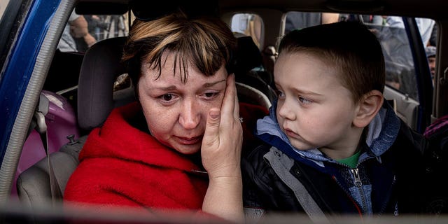 Natalia Pototska, 43, cries as her grandson Matviy looks on in a car at a center for displaced people in Zaporizhzhia, Ukraine, Monday, May 2, 2022.