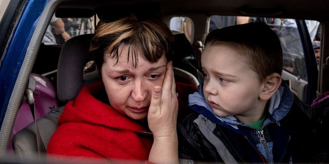 Natalia Pototska, 43, cries as her grandson Matviy looks on in a car at a center for displaced people in Zaporizhzhia, Ukraine, Monday, May 2, 2022.