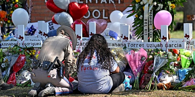 A police officer comforts family members at a memorial outside Robb Elementary School in Uvalde, Texas, on Thursday, May 26.