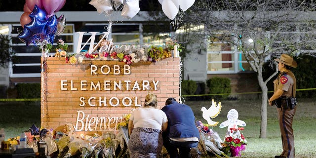 Stephanie and Michael Chavez of San Antonio pay their respects at a makeshift memorial outside Robb Elementary School, the site of a mass shooting, in Uvalde, Texas, U.S., May 25, 2022. 