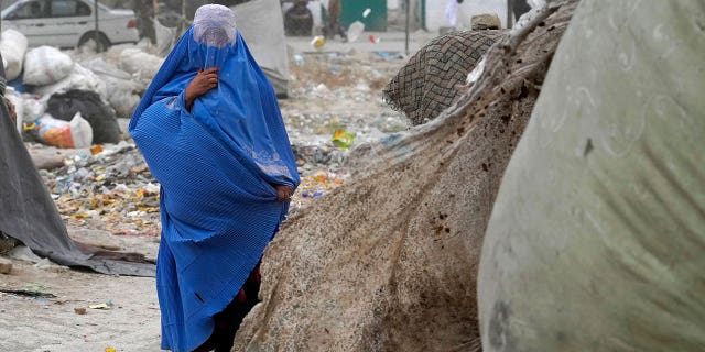 A woman wearing a burqa walks outside her home in Kabul, Afghanistan, Sunday, May 8, 2022.