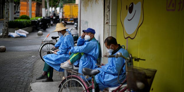 Workers in protective suits rest on a street during lockdown amid the COVID-19 outbreak in Shanghai, China, May 28, 2022.